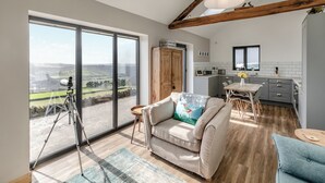 A spacious living area with a large sliding glass door, a cozy sofa, a dining table, and a kitchen area.
