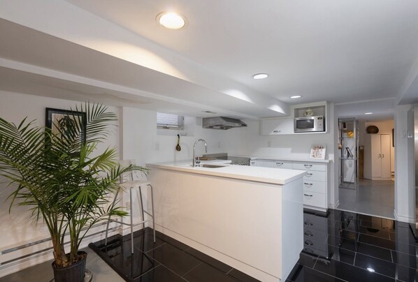 A modern kitchen with white cabinetry, a central island, and black flooring.