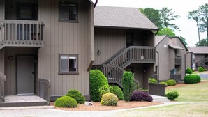 A multi-story residential building with a grey exterior, a central staircase, and a small front porch. - The Duffer's Drop - 2BR/2BA Condo in Pinehurst, NC (Pinehurst)