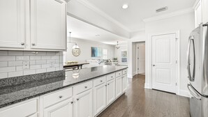 A modern kitchen with white cabinetry, granite countertops, and a stainless steel refrigerator. - Resort Pool - Firepit - Sleeps 10 (Santa Rosa Beach)
