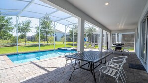 Un espacio al aire libre cubierto con piscina, mobiliario de patio y una parrilla.