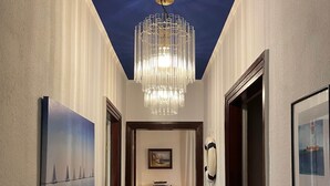 A hallway with a chandelier, a fireplace, and framed artwork on the walls. - Vacation home Beerster Sonne Ideal for a long stay (Gestland)