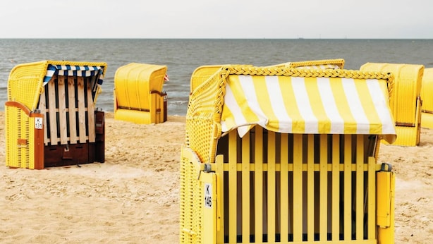 Beach chairs with striped canopies on a sandy beach. - Vacation home Beerster Sonne Ideal for a long stay (Gestland)
