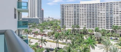 A high-rise hotel with multiple floors, a parking area, and a landscaped courtyard with palm trees.