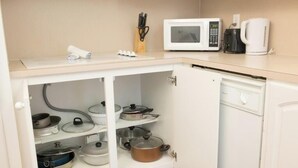 A kitchen with a microwave, coffee maker, and a cabinet with pots and pans. - Komffy Apt w/2 Queen Beds and Canal View at Tides (Hollywood)