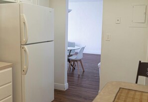 Une cuisine avec un réfrigérateur blanc, des meubles en bois et un coin repas comprenant une table et des chaises blanches.