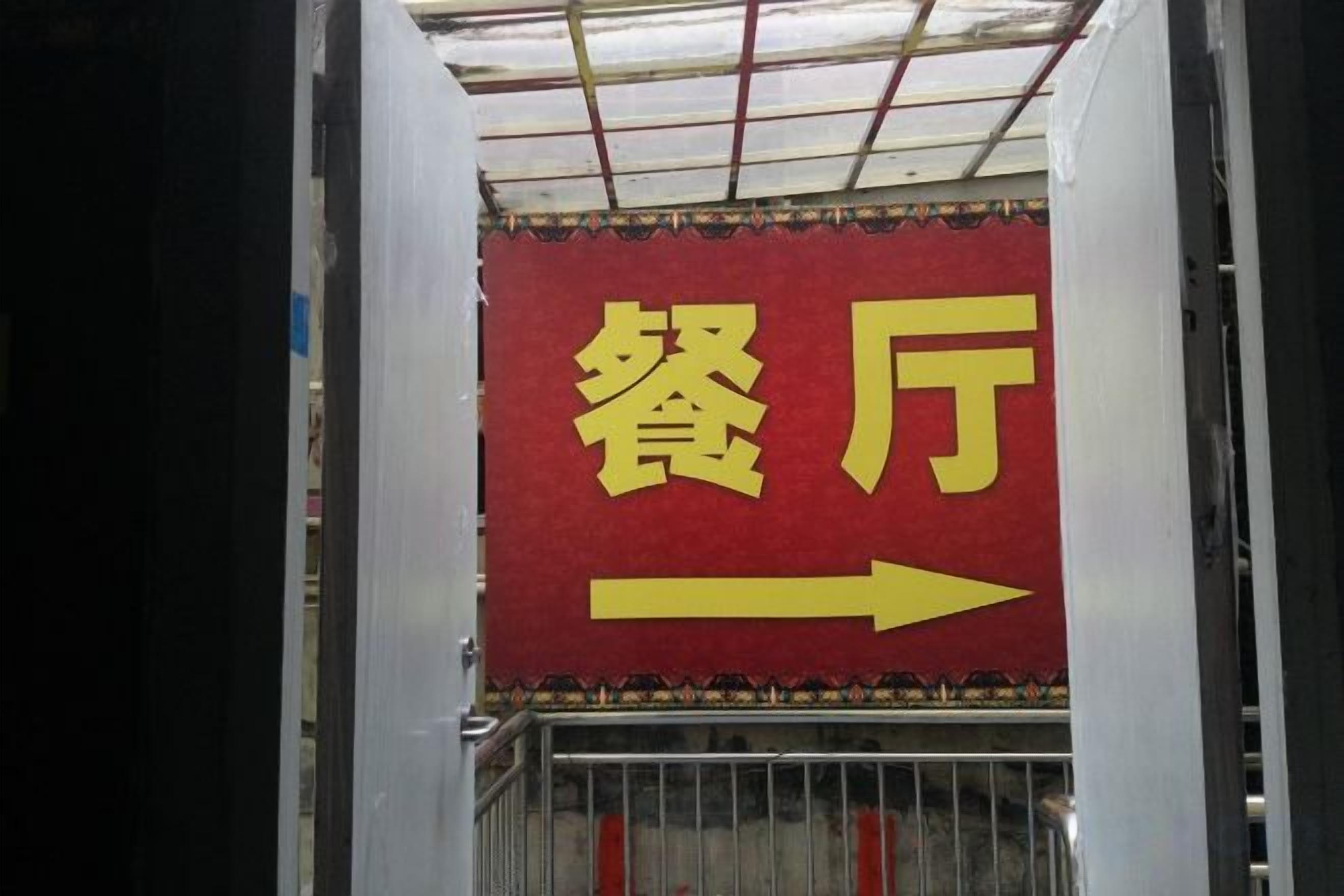 Señal direccional con caracteres chinos que indican 'restaurante' y una flecha que apunta a la derecha.
