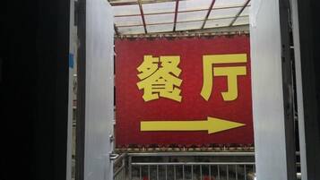 Señal direccional con caracteres chinos que indican 'restaurante' y una flecha que apunta a la derecha.