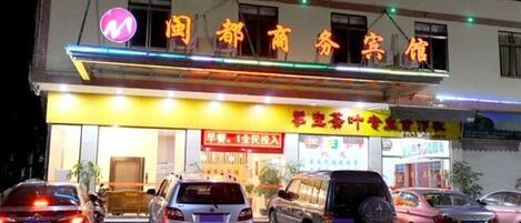 A hotel with a sign indicating it is a business hotel. There are several cars parked in front.