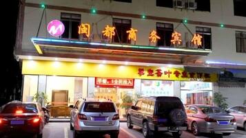 A building with a sign that reads 'International Business Hotel'. There are multiple cars parked in front.