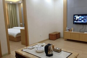 A hotel room with a bed, a TV, a coffee table with tea sets, and a wooden cabinet. - Mindu Business Hotel (Anxi)