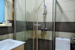 A bathroom with a glass-enclosed shower, a white sink, and a toilet.