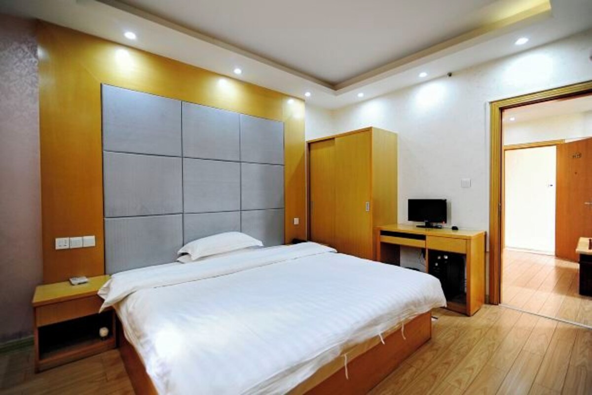 A bedroom with a bed, a desk with a computer, and a wardrobe.