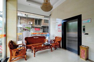 Vestíbulo con un conjunto de sofás, una recepción y una puerta grande, probablemente que da a una zona de servicios.