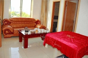 Quarto com sofá de madeira, mesa de centro e cama com cobertura vermelha.