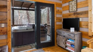 Un accogliente interno di una baita con vasca idromassaggio, televisore e libreria.
