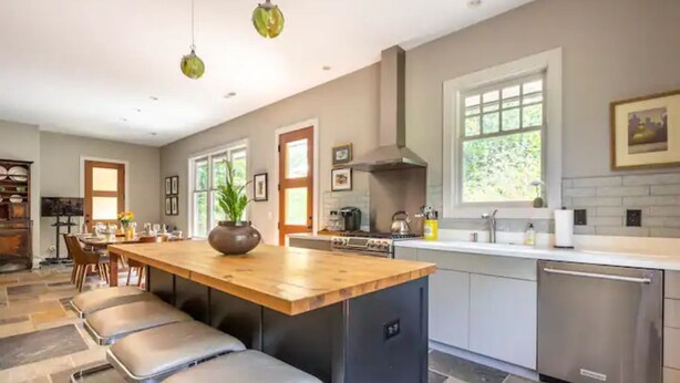 Een moderne keuken met een centraal eiland, roestvrijstalen apparatuur en een groot raam voor natuurlijk licht.