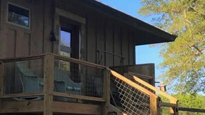 Een houten hutje met een balkon, een raam en een deur.