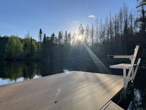 A wooden dock extending into a calm lake, surrounded by dense forest and a clear sky. - Secluded and spacious lake home in Wisconsin Northwoods (Deerbrook)