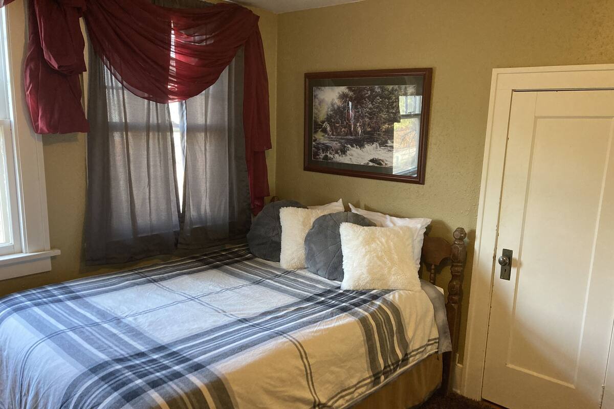 A bedroom with a bed, a painting on the wall, and a door.