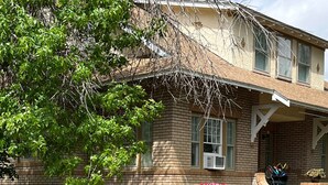 A two-story house with a brick exterior, a front porch, and a stone pathway leading to the entrance. - The Coffey House (Choteau)