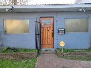 Stylish entrance with a wooden door and large windows, set against a brick pathway.