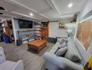 Relax in this stylish living room with a large flat-screen TV, comfortable sofa, and wooden coffee table.
