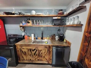 Kitchen features a central island with a sink and wooden cabinet, plus a stove, dishwasher, and trash bin.