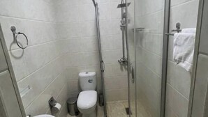 A small, tiled bathroom with a glass-enclosed shower, a toilet, and a sink. - Mazza Plaza(Joy hotel) (Тошкент)