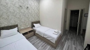 A hotel room with two beds, a small bedside table, and a wardrobe. - Mazza Plaza(Joy hotel) (Тошкент)