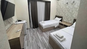 A hotel room with two beds, a desk with a TV, a wardrobe, and an air conditioning unit. - Mazza Plaza(Joy hotel) (Тошкент)