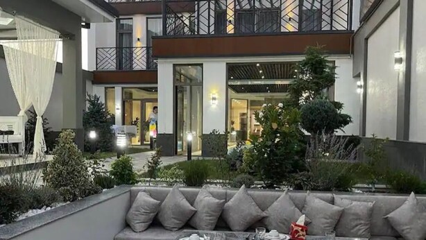 A modern outdoor dining area with a grey sofa and a table set for a meal. - Best place for vacation (Тошкент)
