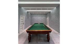 A pool table in a room with grey textured walls and a white door. - Palma Villa (Тошкент)