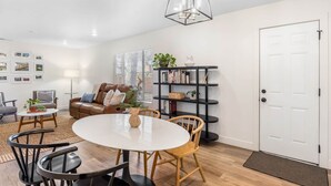 Ein modernes Wohnzimmer mit einem runden Esstisch, einem Ledersofa und einem Bücherregal.