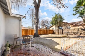 Ein Garten mit Terrasse, Holzzaun und Baum.