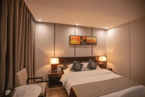 A hotel room with a bed, two bedside lamps, a nightstand, a chair, and a painting on the wall. - Kevin Boutique Hotel (Guilin)