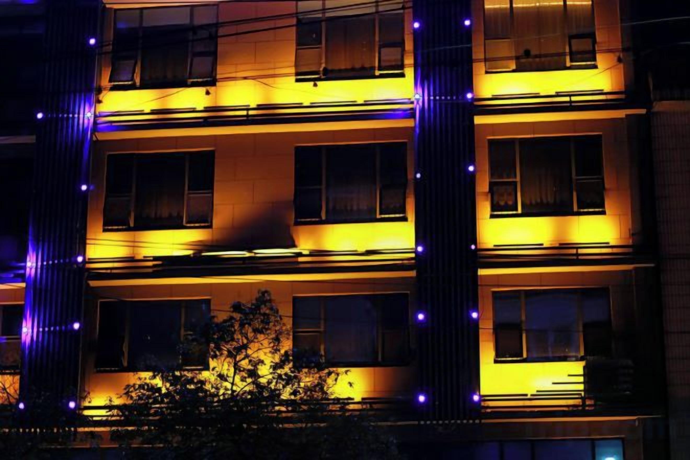 A multi-story building with illuminated windows and vertical light strips.