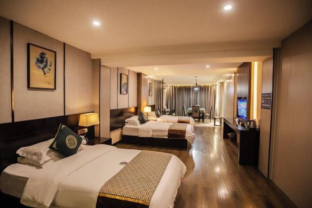 A hotel room with two beds, a TV, a desk, and a bathroom in the background.