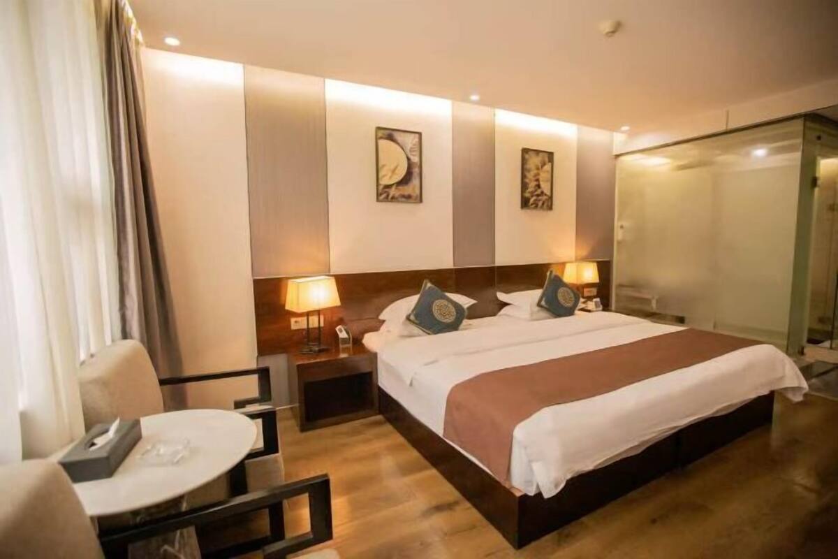 A hotel room with a bed, bedside tables, a desk, and a chair.