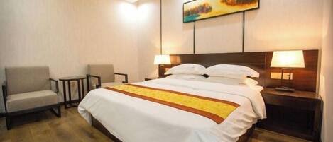 Una habitación de hotel con una cama grande, dos mesitas de noche con lámparas, una silla y un cuadro en la pared.