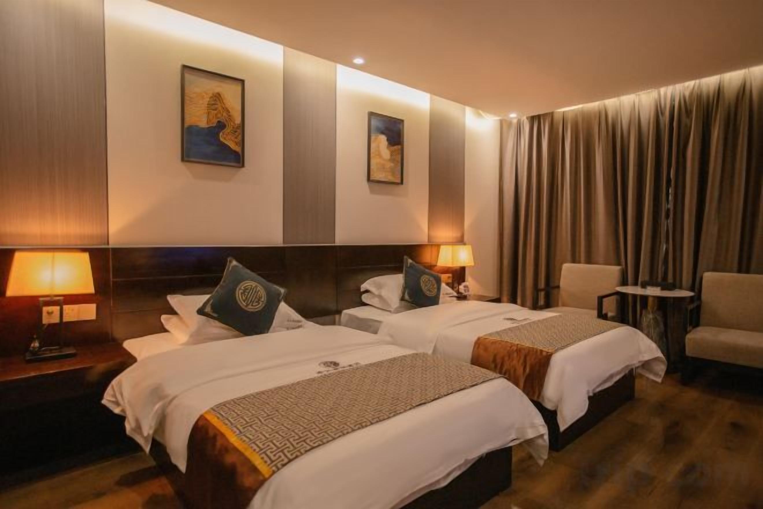 Une chambre d’hôtel avec deux lits, un coin salon et une vue sur la ville.