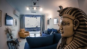 A living room with a blue sofa, a yellow armchair, and a decorative bust. - Pyramids Bay Apartment the best place to view the Giza Pyramids (Giza Governorate)