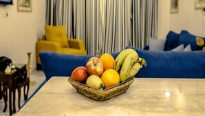 A living room with a blue sofa, a yellow armchair, and a fruit basket on a table. - Pyramids Bay Apartment the best place to view the Giza Pyramids (Giza Governorate)