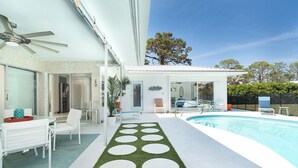 Une maison moderne dotée d’une piscine, d’un espace salon extérieur et d’un patio couvert.