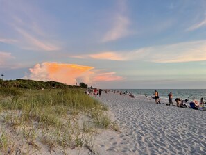 A beach with people relaxing and sunbathing, grassy dunes, and a cloudy sky. - Luxury renovated pool house & separate studio apartment 1.5 miles to the beach. (Englewood)