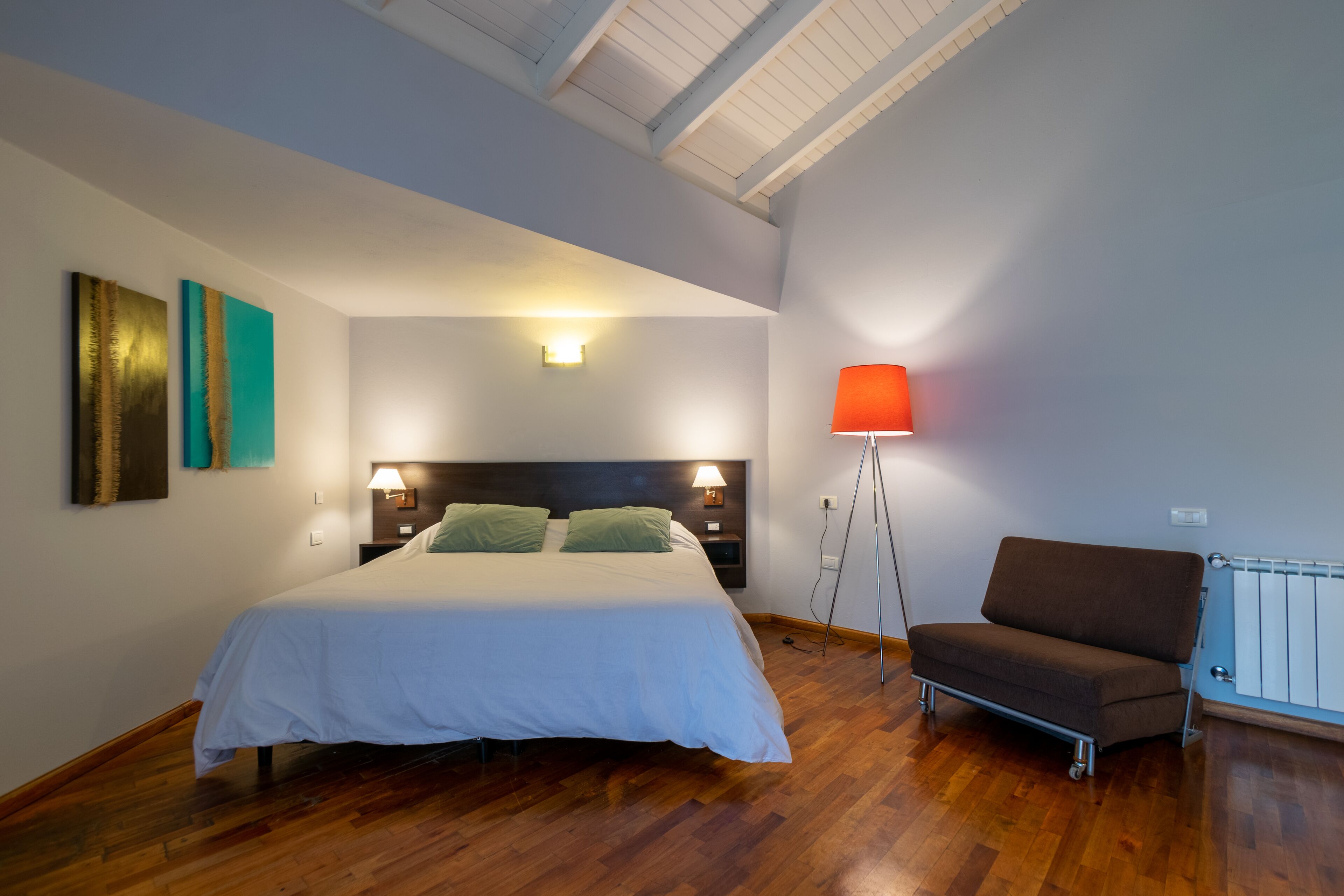 Une chambre à coucher comprenant un lit, des lampes de chevet, une table de chevet, un canapé et une lampe sur pied.