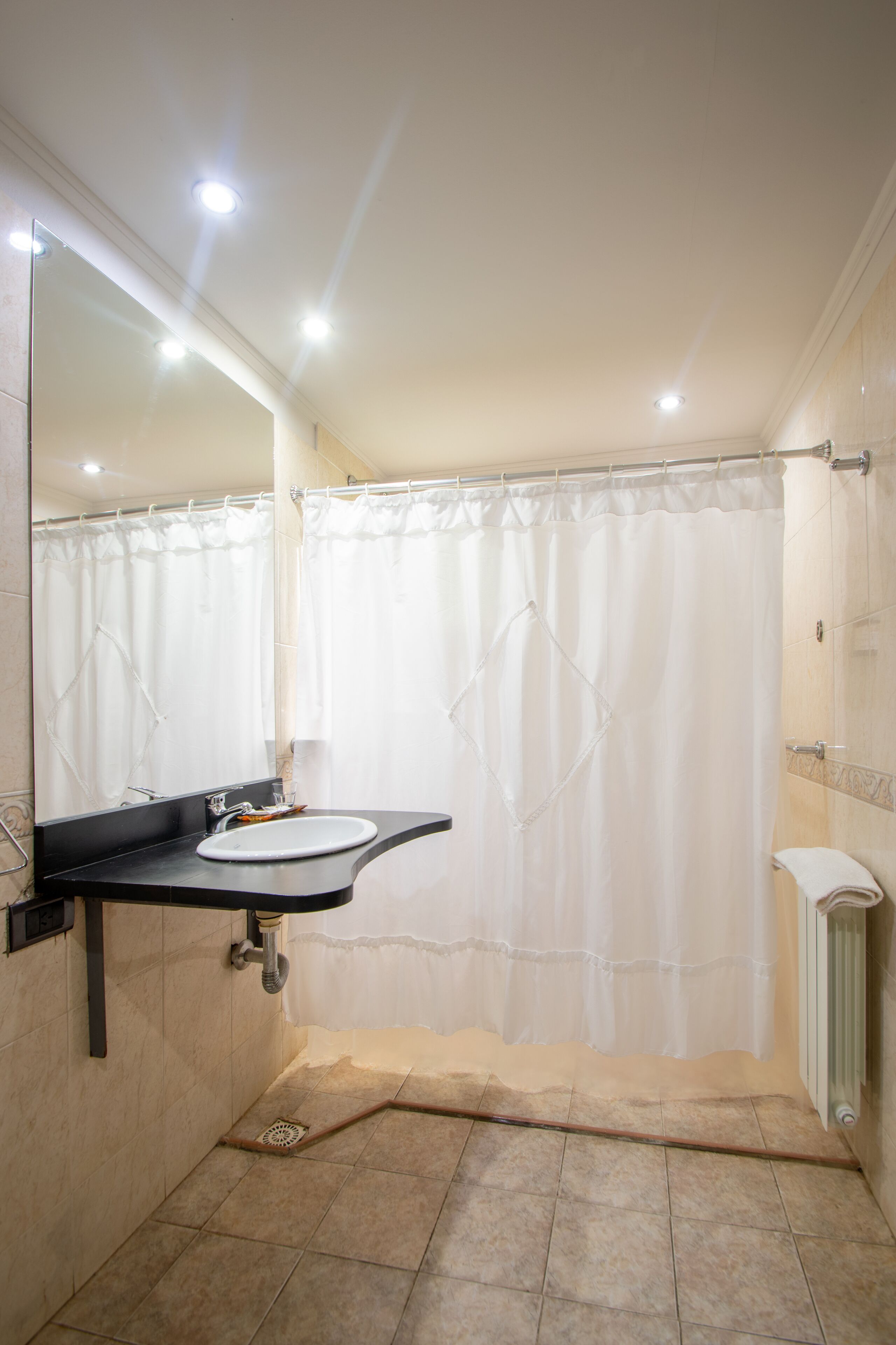 A bathroom with a sink, mirror, shower curtain, and tiled floor.