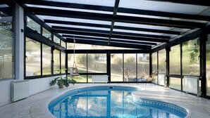 An indoor swimming pool with a glass enclosure, a chair, and a potted plant. - Harmonie Hotel de Montaña (Villa General Belgrano)
