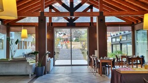 A spacious indoor area with a high wooden ceiling, large windows, and a view of the outside. - Harmonie Hotel de Montaña (Villa General Belgrano)