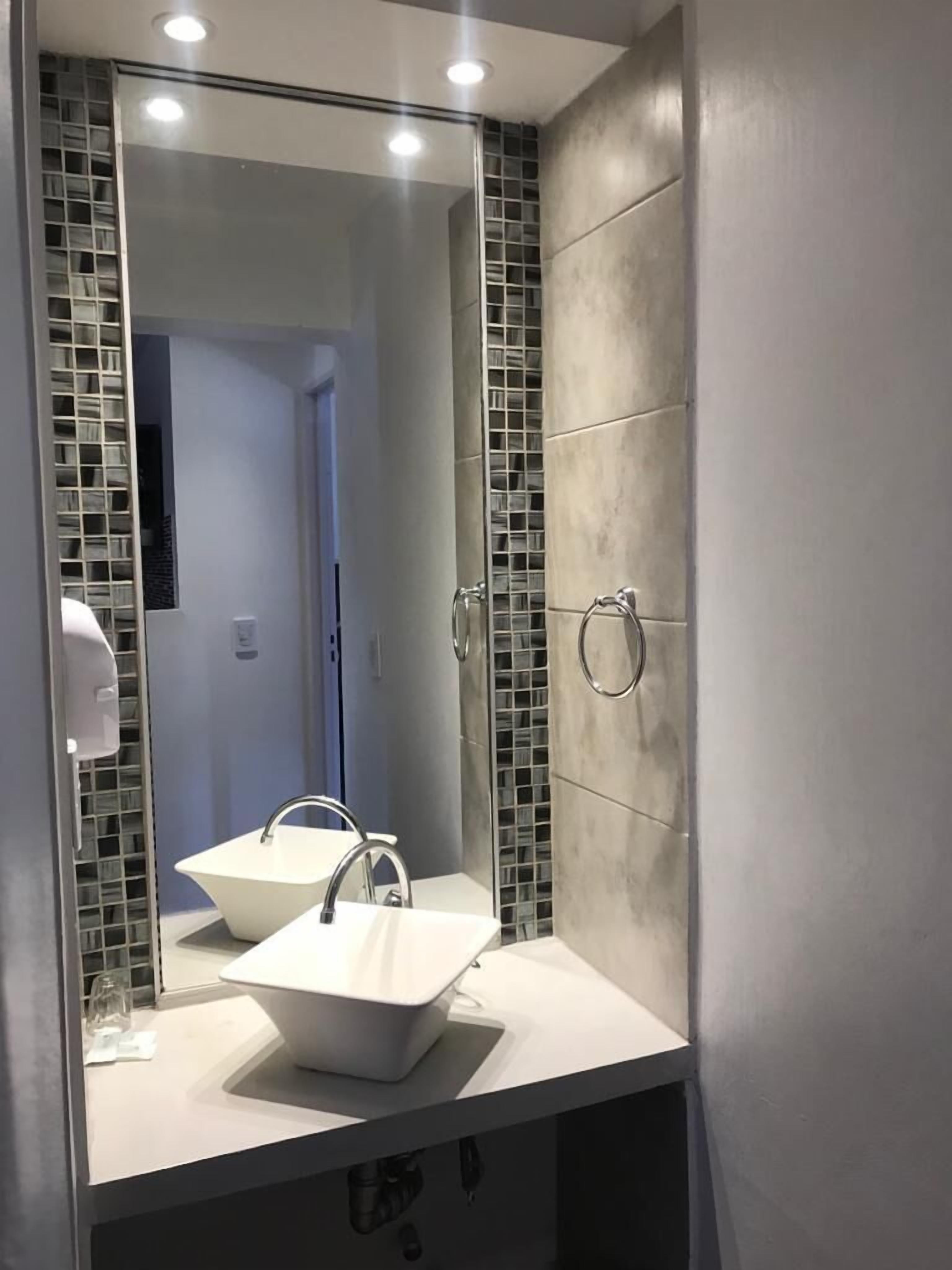 Een badkamer met een grote spiegel, twee wastafels en een handdoekrek.